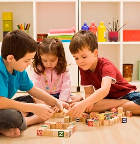 tres niños jugando con bloques de madera